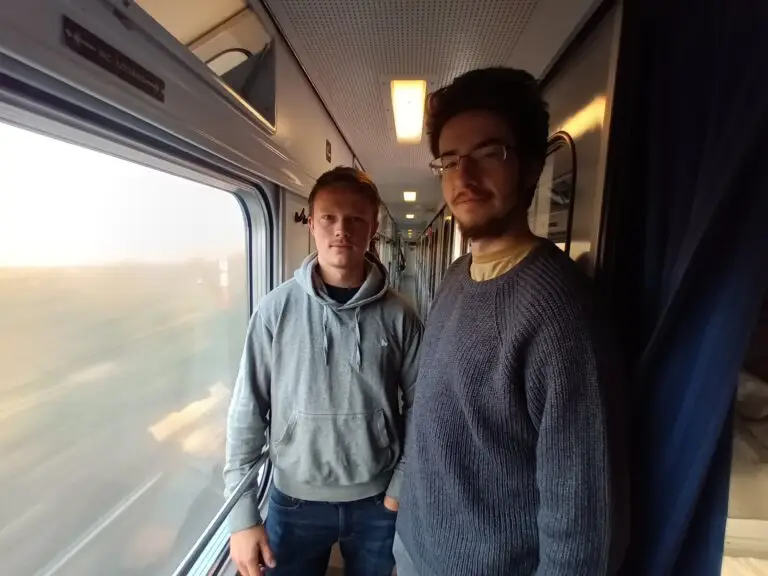 [:en]Two young men in the train aisle.[:]