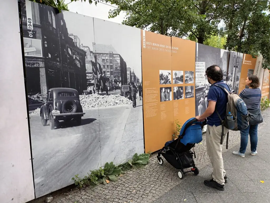 [:en]People look at pictures of Checkpoint Carlie's history on the site of the Berlin Wall.[:]