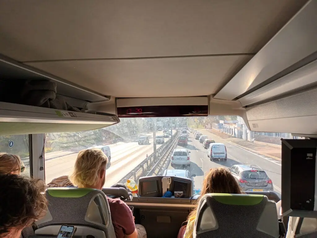 [:en]People are sitting in the upper deck of the double-decker bus and watching Prague approaching through the front window.[:]