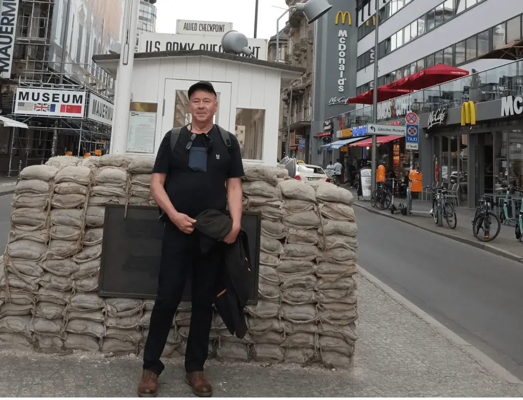[:en]Administrator of these websites. A man is standing at the Checkpoint Charlie guard post. There are small sandbags behind him.[:]