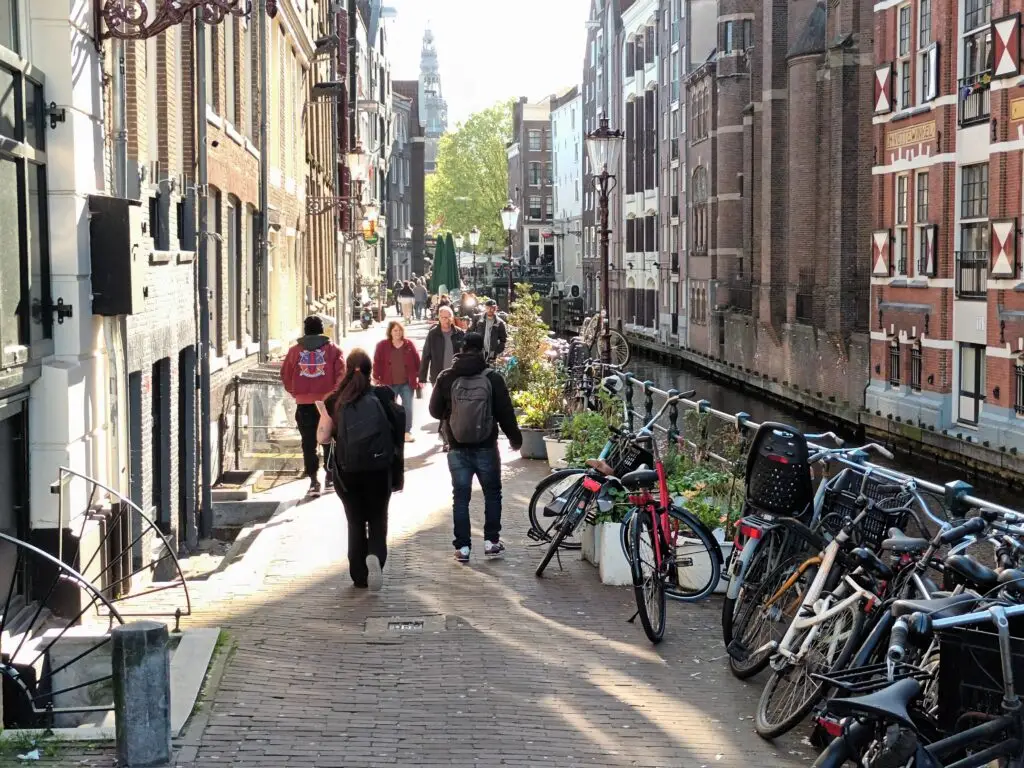 [:en]Amsterdam's narrow walkway. People are walking and bicycles are parked.[:]