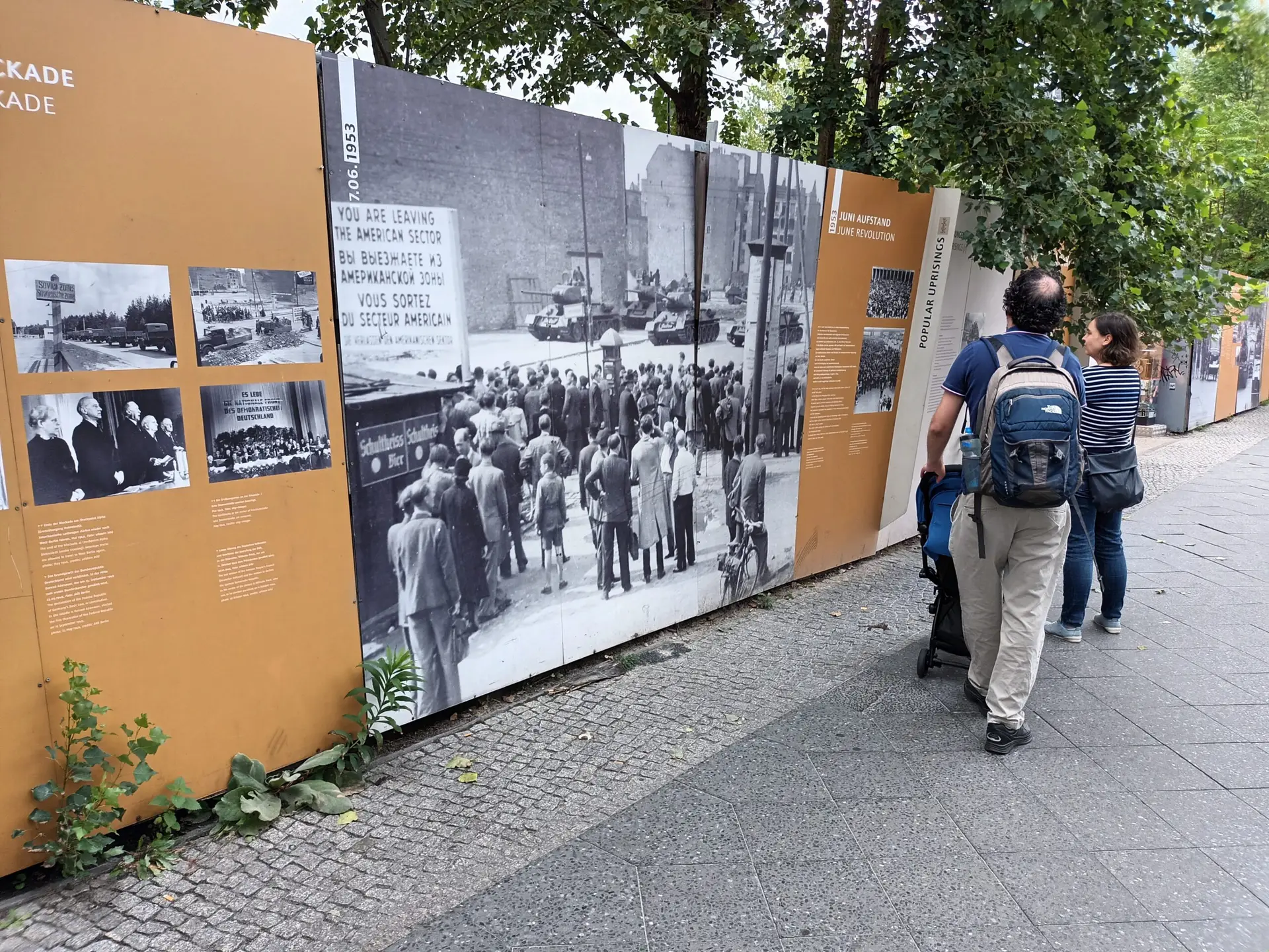 [:en]Historical photographs attached to the wall along the street. Visitors are watching.[:]
