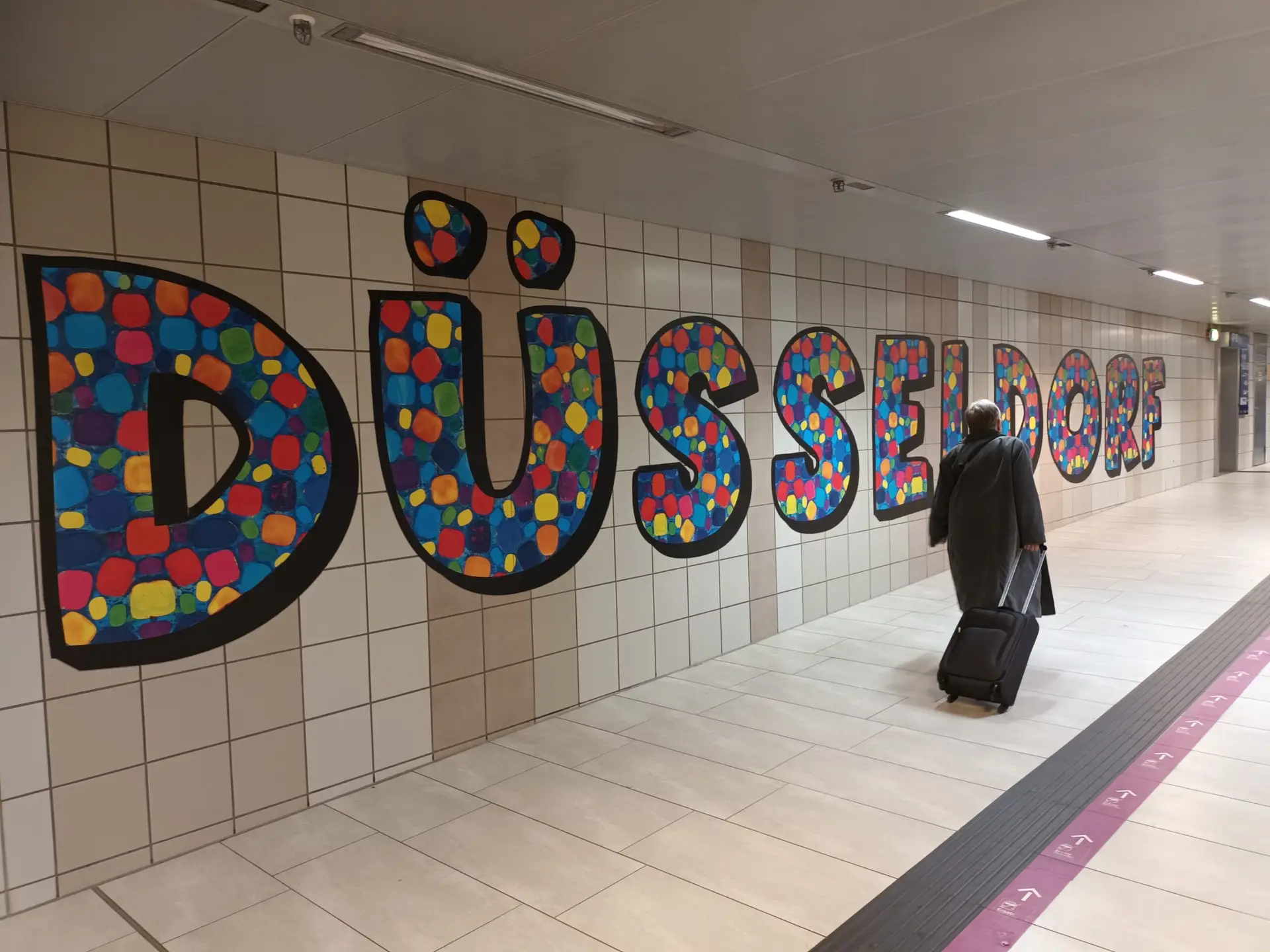 [:en]Düsseldorf text on the wall of the train station corridor.[:]