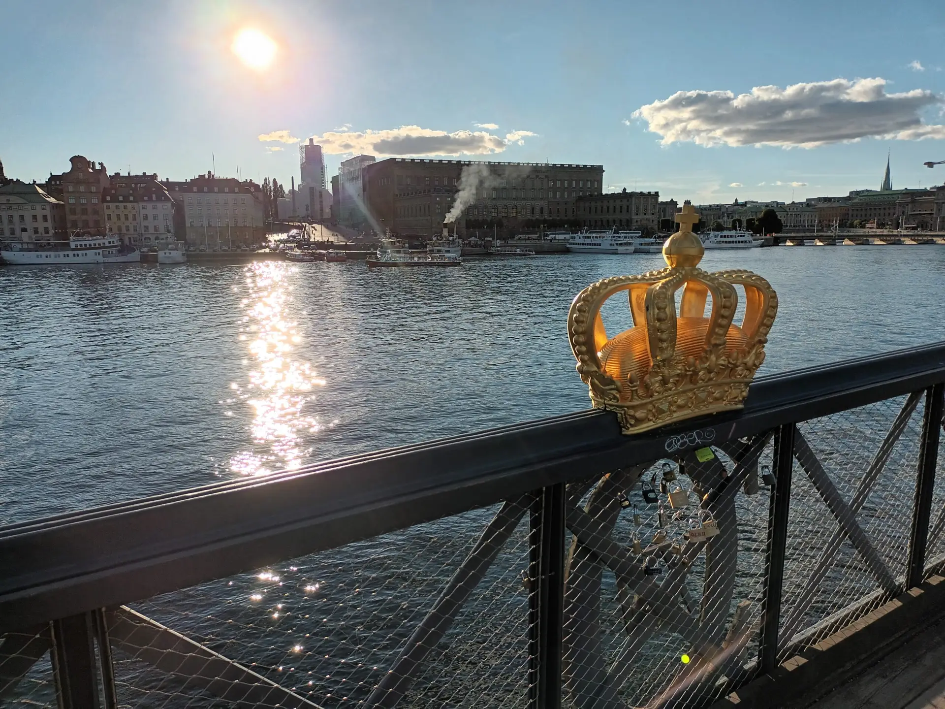 [:en]Stockholm`s Royal Palace pictured from a bridge with a crown on a railing.[:]