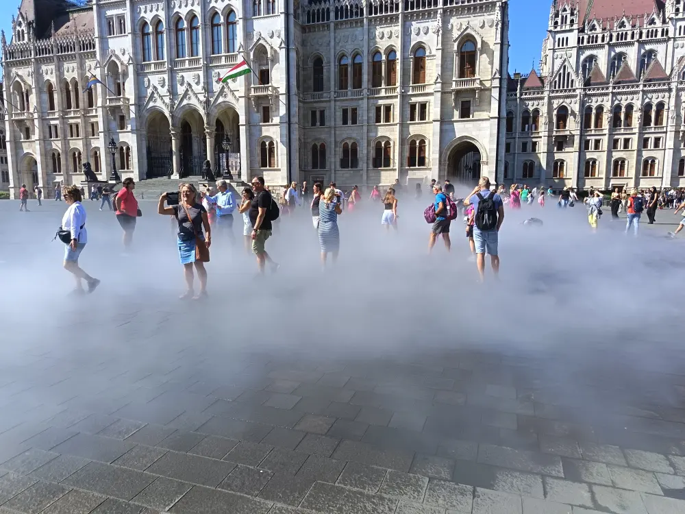 The nozzles are spraying water from the pavement and people are enjoying it.