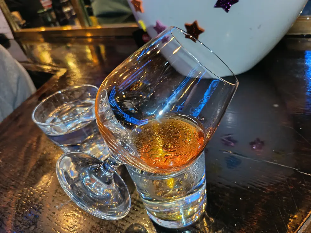 The drink is kept at a suitable temperature when it is placed on its side on top of a glass of water.