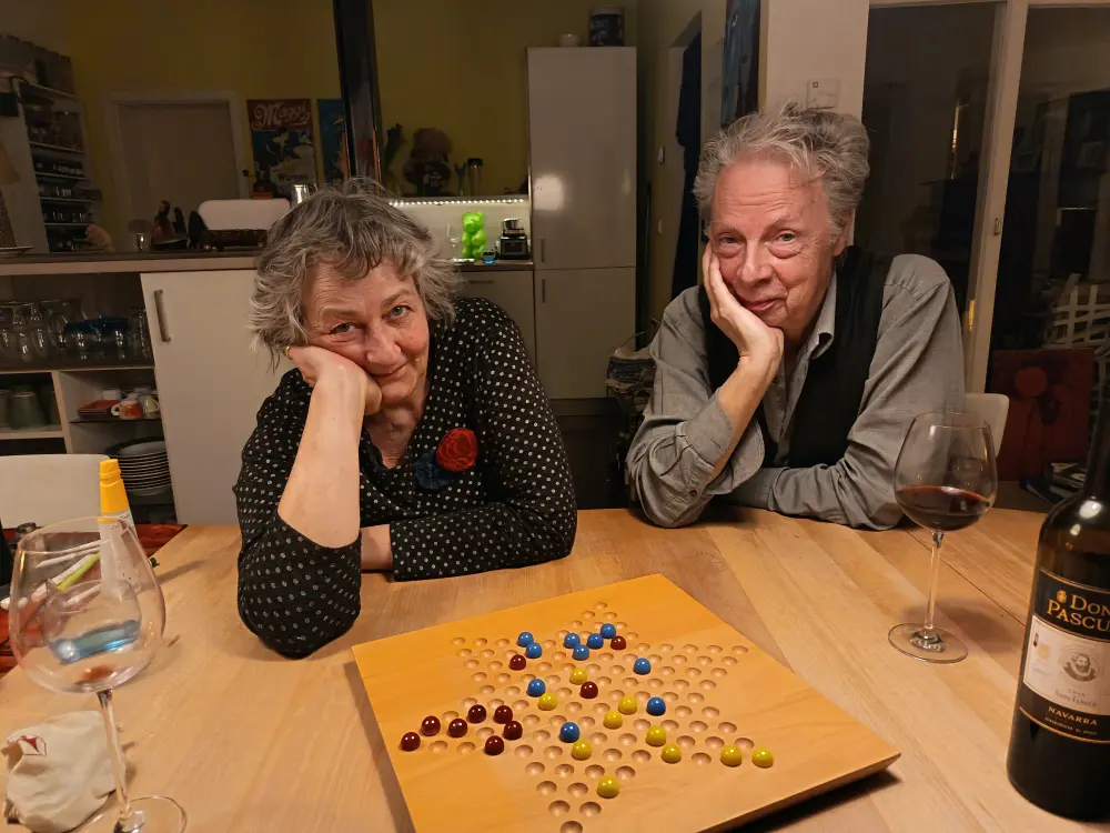 A man and a woman are playing a board game and looking at the camera.