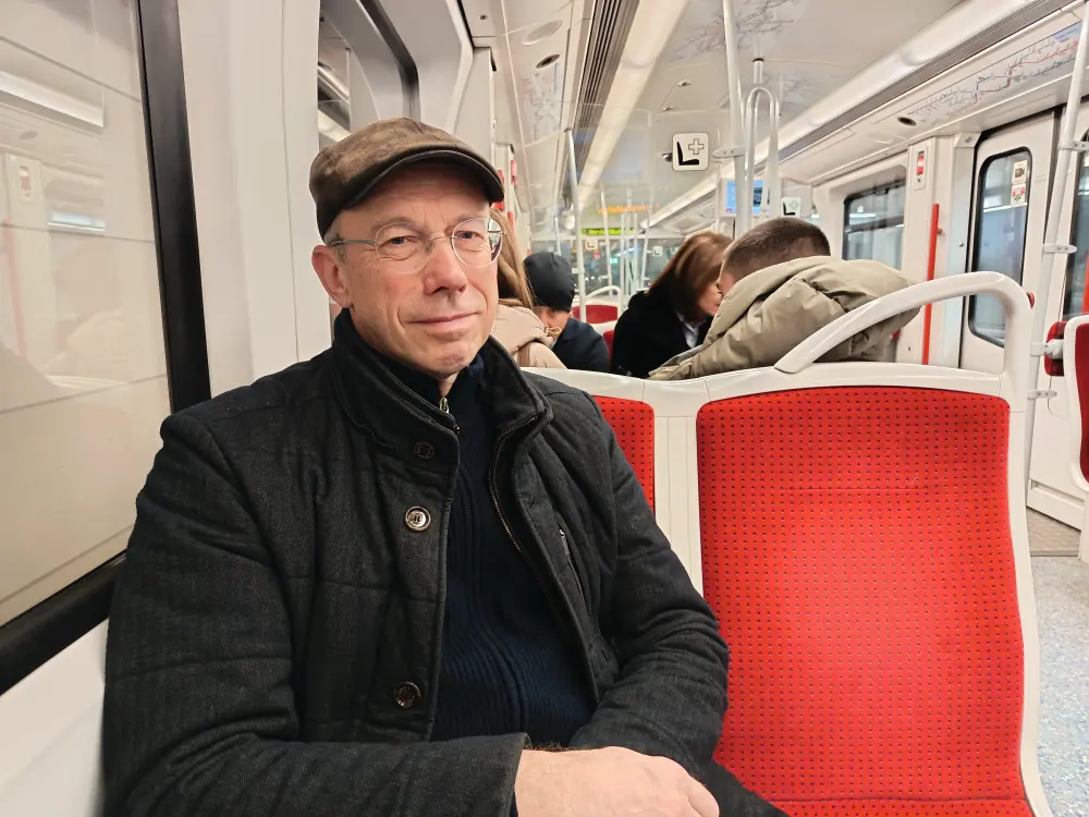 A man sits on a tram seat.